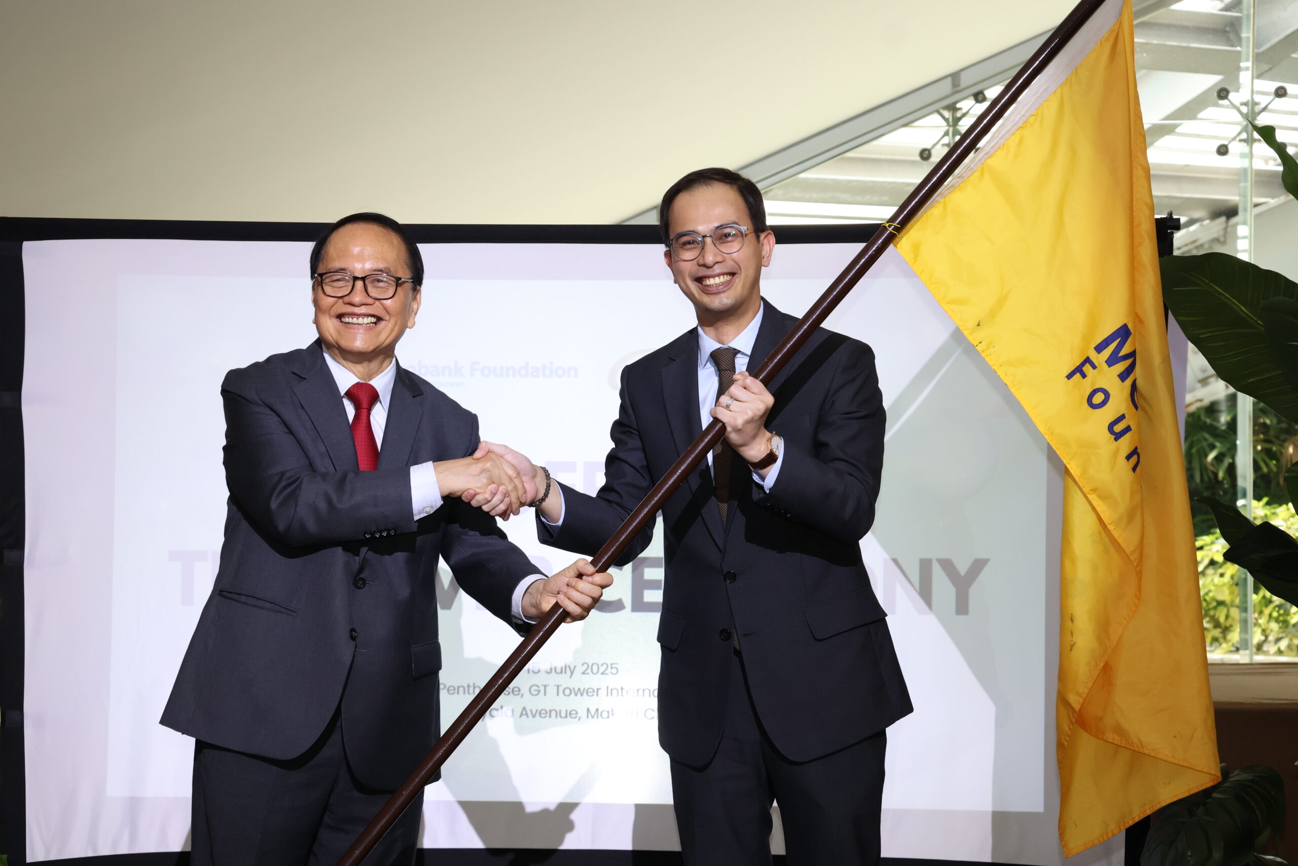 Outgoing Metrobank Foundation (MBFI) President and GT Foundation (GTFI) Executive Director Aniceto M. Sobrepeña symbolically passes the MBFI banner to his successor, incoming President and Executive Director Philip Francisco U. Dy, marking the formal handover of leadership of both foundations.