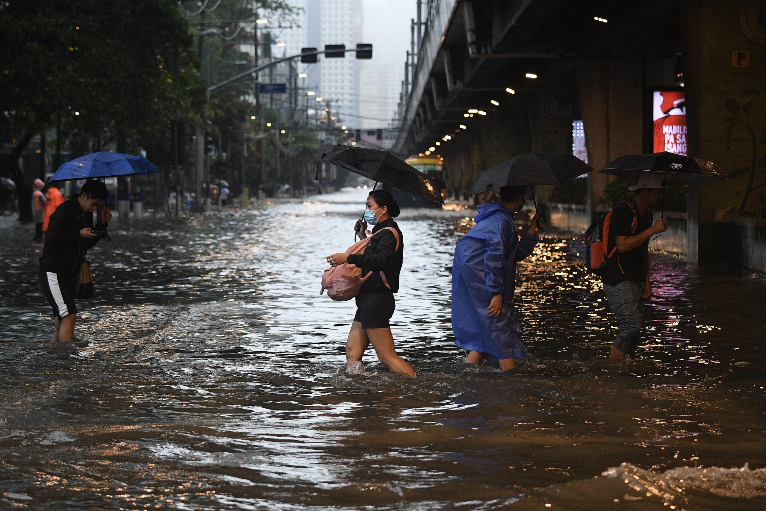 Pedestrians cross a flooded street in Manila.