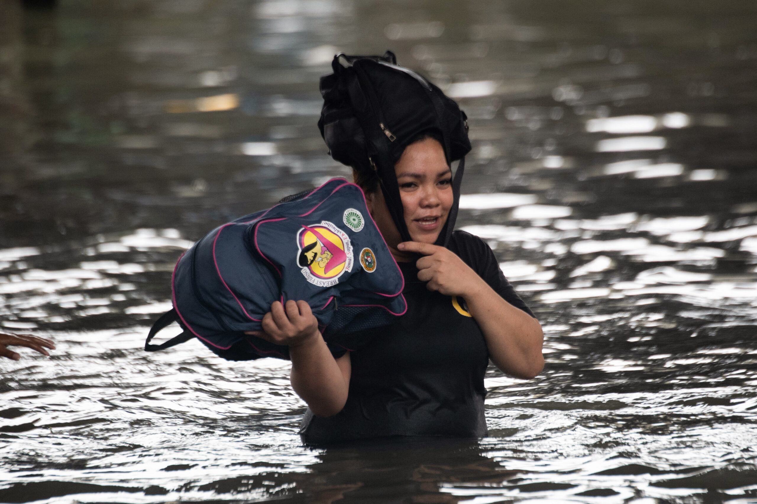 A woman carrying her belongings wades through a flooded street in Manila on July 21, 2025, after Typhoon Wipha brought heavy rains and flooding to the Philippines, where two people have been reported missing, according to the country's National Disaster Risk Reduction and Management Council. (Photo by Ted ALJIBE / AFP) (Photo by TED ALJIBE/AFP via Getty Images)
